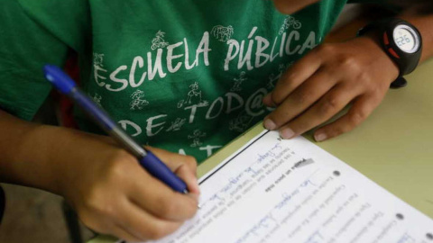 Un alumno de Madrid rellena una ficha con la camiseta en apoyo de la educación pública. EFE