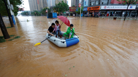 Unos ciudadanos utilizan un bote inflable para moverse en la zona inundada de Jiujiang en la provincia de Jiangxi, China. REUTERS/Stringer