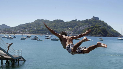 Un joven salta en el Real Club Náutico de San Sebastián, donde se ha podido disfrutar de una jornada playera en el último día de la primavera. EFE/Javier Etxezarreta