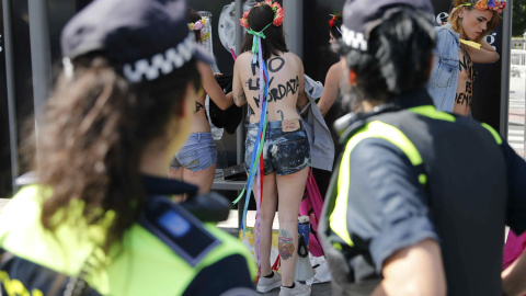 Dos policías municipales observan a las activistas de Femen que se han encaramado hoy en una acción sorpresa a la fuente de Cibeles para protestar contra la ley mordaza.- EFE/Juan Carlos Hidalgo