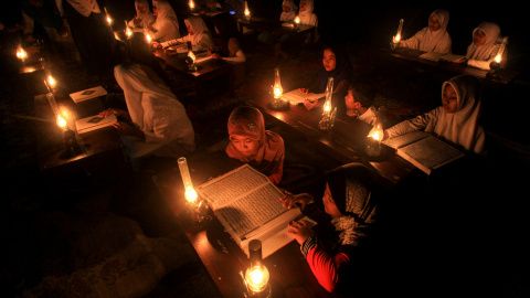 Estudiantes leen el Corán al aire libre iluminados por lámparas de aceite para celebrar el " Nuzul al- Corán " en Solo , Java Central, Indonesia.- REUTERS