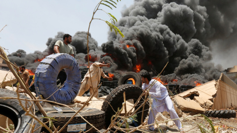 Trabajadores mueven neumáticos de un almacén después de un incendio en una zona industrial en Karachi , Pakistán.- REUTERS / Akhtar Soomro