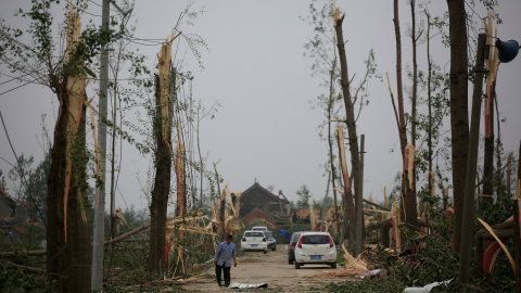 Un aldeano camina por un camino dañado tras el paso de un tornado que golpeó este jueves a Yancheng , China.- REUTERS / Aly canción