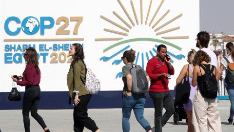 Varias personas caminan junto al cartel de la COP27 en Sharm El Sheikh, Egipto.
