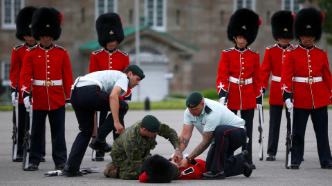 Un miembro de la guardia de honor es atendido por sus colegas tras sufrir un desmayo antes de pasar revista el presidente de México, Enrique Peña Nieto en Quebec, Canadá. REUTERS / Mathieu Belange