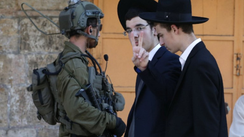 Dos colonos judíos pasan junto a un soldado israelí en Hebrón. - AFP