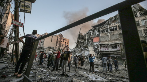 Un grupo de palestinos inspeccionan los restos de una torre destruida por un bombardeo israelí. Un grupo de palestinos inspeccionan los restos de una torre destruida por un bombardeo israelí.