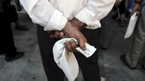Un pensionista espera con su ticket de prioridad para recibir su pensión en una sucursal de National Bank en Atenas, Grecia, hoy. REUTERS/Alkis Konstantinidis