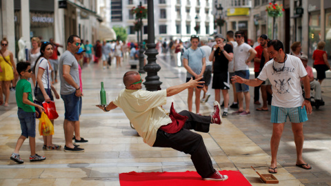 Un artista callejero disfrazado de camarero actúa en una calle de Málaga.  REUTERS/Jon Nazca.