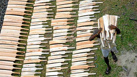 Un hombre coloca bates de cricket de softbol a lo largo de unas vías de tren para secarlas después de pintarlas en Panadura , Sri Lanka.- REUTERS / Dinuka Liyanawatte