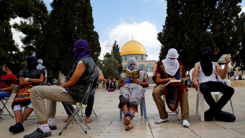 Palestinos enmascarados leen el Corán antes de confontarse con la policía israelí, cerca de la Cúpula de la Roca en el compuesto conocido por los musulmanes como Noble Santuario y para los judios como el Monte del Templo en la Ciudad Vieja 