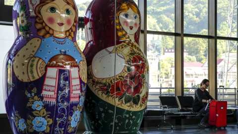Una mujer se sienta junto a las muñecas matryoshka gigantes dentro de una terminal del aeropuerto de Sochi en Adle , Rusia, 13 de julio de 2015. Rusia será la sede la Copa Mundial de la FIFA en 2018. REUTERS / Maxim Shemetov