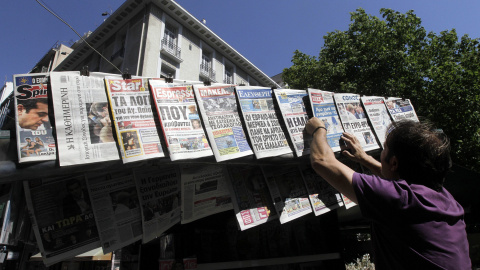 Un ciudadano lee las portadas de los diarios en un quiosco en el centro de Atenas (Grecia) hoy. Los líderes de la eurozona sortearon el abismo de la salida de Grecia del euro y de que ello arrastrara al resto de la eurozona a un terreno des