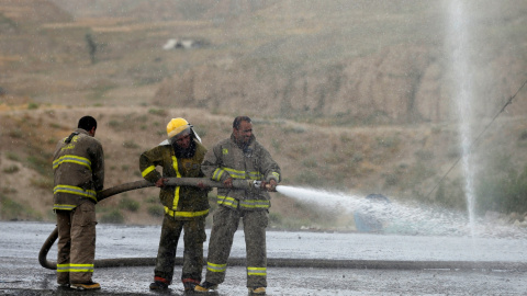 Bomberos afganos lavan la carretera en el sitio de un ataque suicida al oeste de Kabul, Afganistán.- REUTERS / Mohammad Ismail