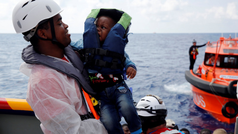 Un mediador cultural del italiano ONG EMERGENCIA lleva un bebé migrante a bordo del barco de rescate para inmigrantes Aid Station Marino ( MOEA ).-REUTERS / Darrin Zammit