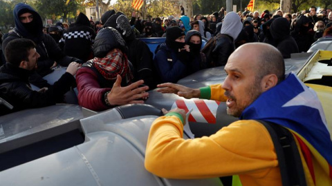 Un manifestante independentista trata de impedir que un grupo de encapuchados vuelquen contenedores en las inmediaciones de la Llotja de Mar de Barcelona/EFE