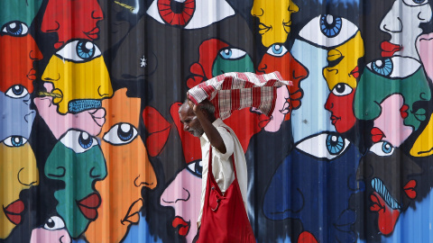 Un hombre se coloca el pañuelo al pasar al lado de un muro en una calle de Nueva Delhi, India. 16 de julio, 2015. REUTERS/Anindito Mukherjee