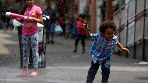 Un niño corre a través del agua que emana una boca de incendio en el barrio neoyorquino de Queens.  REUTERS/Shannon Stapleton.