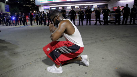 Un joven se arrodilla frente a los policías desplegados en la esquina de Ross Avenue y Griffin street durante la manifestación contra la violencia policial hacia los negros en EEUU./ EFE Un joven se arrodilla frente a los policías desplegados en la esquina de Ross Avenue y Griffin street durante la manifestación contra la violencia policial hacia los negros en EEUU./ EFE