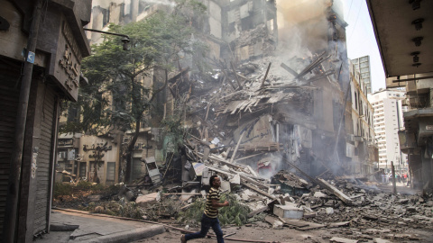 Un hombre corre junto al un edificio en llamas en el distritito de Fagala, en el centro de El Cairo (Egipto) hoy, 20 de julio de 2015. El incendio, que habría empezado en un almacén de papel, se extendió a los edificios aledaños y provocó u