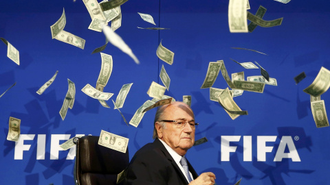 El presidente de la FIFA, Joseph Blatter, bajo una lluvia de billetes que le lanzó el humorista británico Simon Brockin, durante una rueda de prensa para presentar los resultados de la reunión del Comité Ejecutivo de la FIFA en su sede de Z