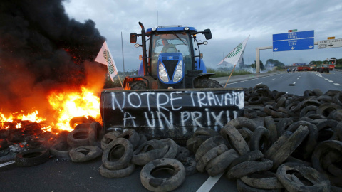 Un ganadero francés utiliza su tractor para alimentar con llantas una barricada y bloquear la autopista A1 Lille-París./ REUTERS. Pascal Rossignol