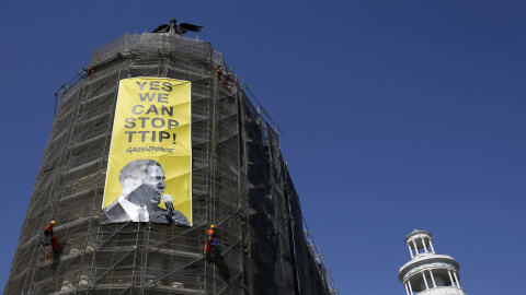 Activistas de Greenpeace cuelgan una pancarta con la imagen del presidente Barack Obama en la que se puede leer "Sí podemos parar el TTIP", en el edificio Metrópolis de la Gran Vía la calle en Madrid. REUTERS/Javier Barbancho