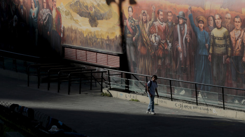 Un hombre camina al lado de un mural que representa personajes históricos de la época de la dominación española hasta los tiempos modernos en La Paz, Bolivia. REUTERS / David Mercado