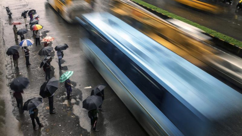Un grupo de personas se protege de la lluvia en Bombay, India. Al menos 24 personas han muerto y 9 se encuentran desaparecidas por las fuertes lluvias caídas en los últimos días en el estado central indio de Madhya Pradesh.  EFE/Divyakant S