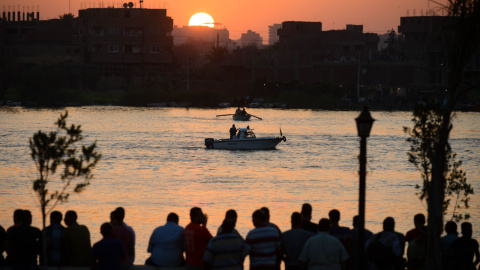 Familiares observan al equipo de rescate buscar víctimas en el río Nilo, al norte de El Cairo, después de que al menos 18 personas murieron cuando un buque de carga golpeó su barco donde celebraban una fiesta. AFP PHOTO / STR