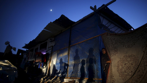 Una mujer palestina se asoma desde un refugio improvisado cerca de su casa, que según testigos, fue destruida por los bombardeos israelíes durante una guerra de 50 días el verano pasado, en la ciudad de Beit Hanoun, en el norte de la Franja