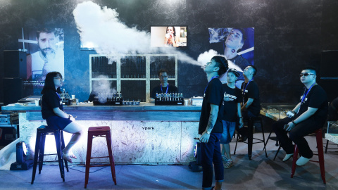 Un empleado fuma un cigarrillo electrónico para atraer a posibles consumidores en la feria "Vape China Expo" del cigarrillo electrónico y el vapor en un centro de exhibiciones de Pekín (China) hoy, 23 de julio de 2015. A pesar de que los be