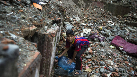 Un niño nepalí vestido con una camiseta del FC Barcelona llena un bidón de agua en Thamel, Katmandú (Nepal) hoy, 23 de julio de 2015. Tras los graves destrozos causados por el terremoto que asoló Nepal el pasado mes de abril los locales se 