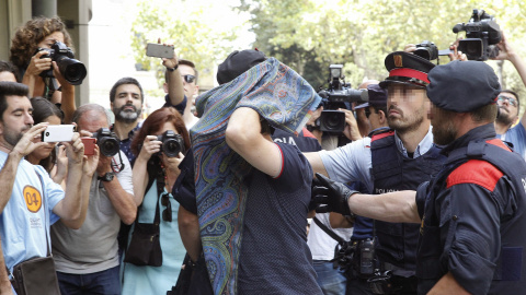 Mossos d'Esquadra y Policía Nacional custodian a una de las personas detenidas hoy en una operación en Barcelona en la que se prevé detener a once personas acusadas de blanquear 10 millones de euros vinculados al crimen organizado con la co