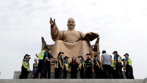 Varios policías surcoreanos detienen a miembros de un sindicato de trabajadores a tiempo parcial durante una protesta contra la política laboral del Gobierno en una calle principal de Seúl, Corea del Sur. EFE/Jung Byung-Hyuk.