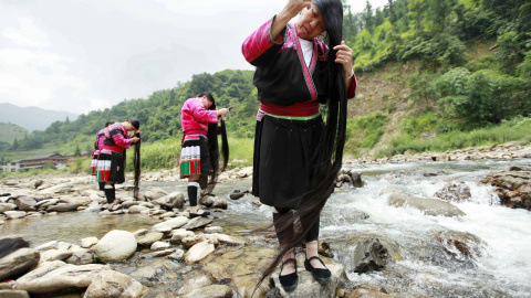 Mujeres de la minoría étnica Yao se cepillan el pelo cerca de un arroyo, en la aldea de Huangluo de Guilin, Región Autónoma Zhuang de Guangxi, China, 23 de julio de 2015. El pueblo, conocido por el largo cabello de sus residentes femeninos,