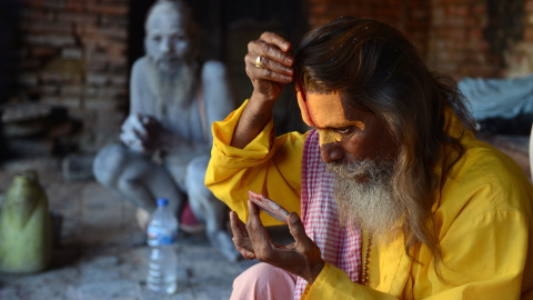 Un sadhu (hombre santo) se colorea la cara con una pasta especial en el templo de Pashupatinath en Katmandú, el 27 de julio de 2015. Decenas de sadhus viven alrededor del templo para dedicar su vida a Shiva, el dios hindú de la destrucción.
