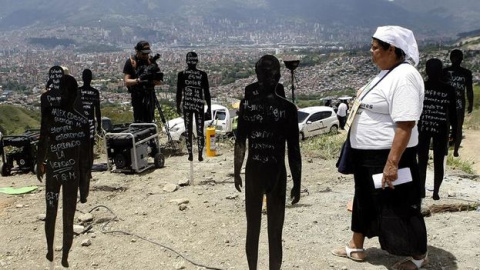 La familiar de uno de los desaparecidos de la Comuna 13, en Medellín, camina entre siluetas que representan a las víctimas enterradas en el lugar. La familiar de uno de los desaparecidos de la Comuna 13, en Medellín, camina entre siluetas que representan a las víctimas enterradas en el lugar.