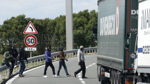 Varios inmigrantes cruzan una carretera cerca de la entrada del Eurotúnel, en Coquelles, cerca de Calais, Francia. EFE/YOAN VALAT