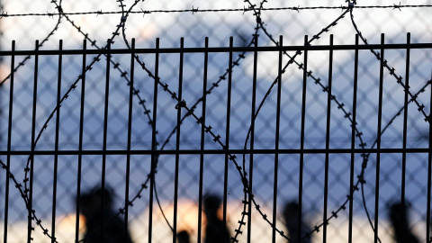 Inmigrantes cruzan una valla al tratar de llegar al tren que los conduce a Inglaterra. EFE/YOAN VALAT