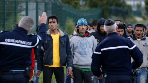 Policía para a inmigrantes que caminan para tratar de llegar al tren que los conduce a Inglaterra. EFE/YOAN VALAT
