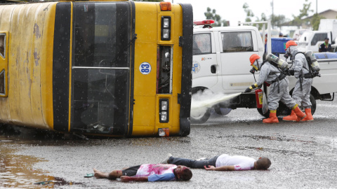 Los servicios de bomberos y rescate, vestidos con trajes especiales, realizan un simulacro con "heridos" al lado de un autobús, mientras apagan un incendio químico en la ciudad de Cebú, Filipinas, 31 de julio de 2015. REUTERS / Charlie Sace