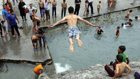 Un niño salta a la piscina de Cheshme-Ali en la antigua ciudad iraní de Ray, en la provincia de Teherán. Irán sufre una ola de calor con temperaturas que rondan los 40 grados. EFE/Abedin Taherkenareh