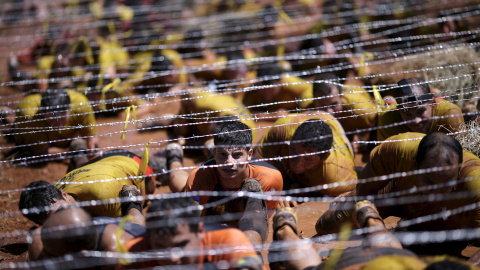 Competidores se arrastran debajo del alambre en la Carrera Bravus en Brasilia. La carrera desafía a los competidores con varios obstáculos en un trayecto de hasta 15 km. REUTERS / Ueslei Marcelino