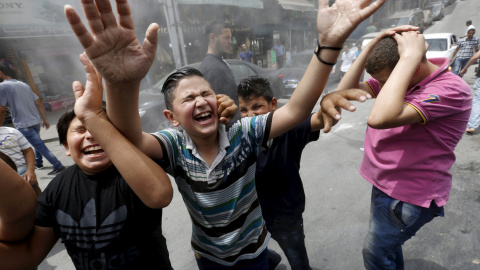 Estos niños son rociardos con un aspersor de agua para enfriarlos, como medida para aliviar el efecto de una ola de calor, en Ammán, Jordania, 3 de agosto de 2015. REUTERS / Muhammad Hamed
