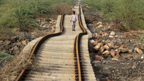 Un aldeano camina sobre las vías del tren que fueron dañadas por las fuertes lluvias monzónicas cerca de la aldea Patdi en Gujarat, 3 de agosto de 2015. REUTERS / Dave Amit