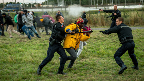 Gendarmes franceses tratan de detener inmigrantes que intentan cruzar el Eurotunel camino a Inglaterra.- PHILIPPE HUGUEN (AFP)