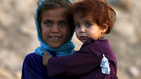 Una niña coge a su hermana en brazos al lado de su casa en Kabul, Afghanistán. 4 de agosto 2015. REUTERS/Omar Sobhani
