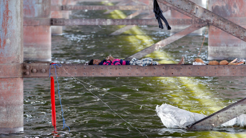 Un hombre duerme en una viga entre los dos pilares de un puente sobre el río Sabarmati durante un día caluroso en Ahmedabad, India. REUTERS/Amit Dave
