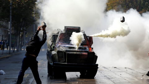 Un estudiante chileno protesta delante de un vehículo policial por la reforma de la educación. Santiago, Chile. REUTERS/Ivan Alvarado